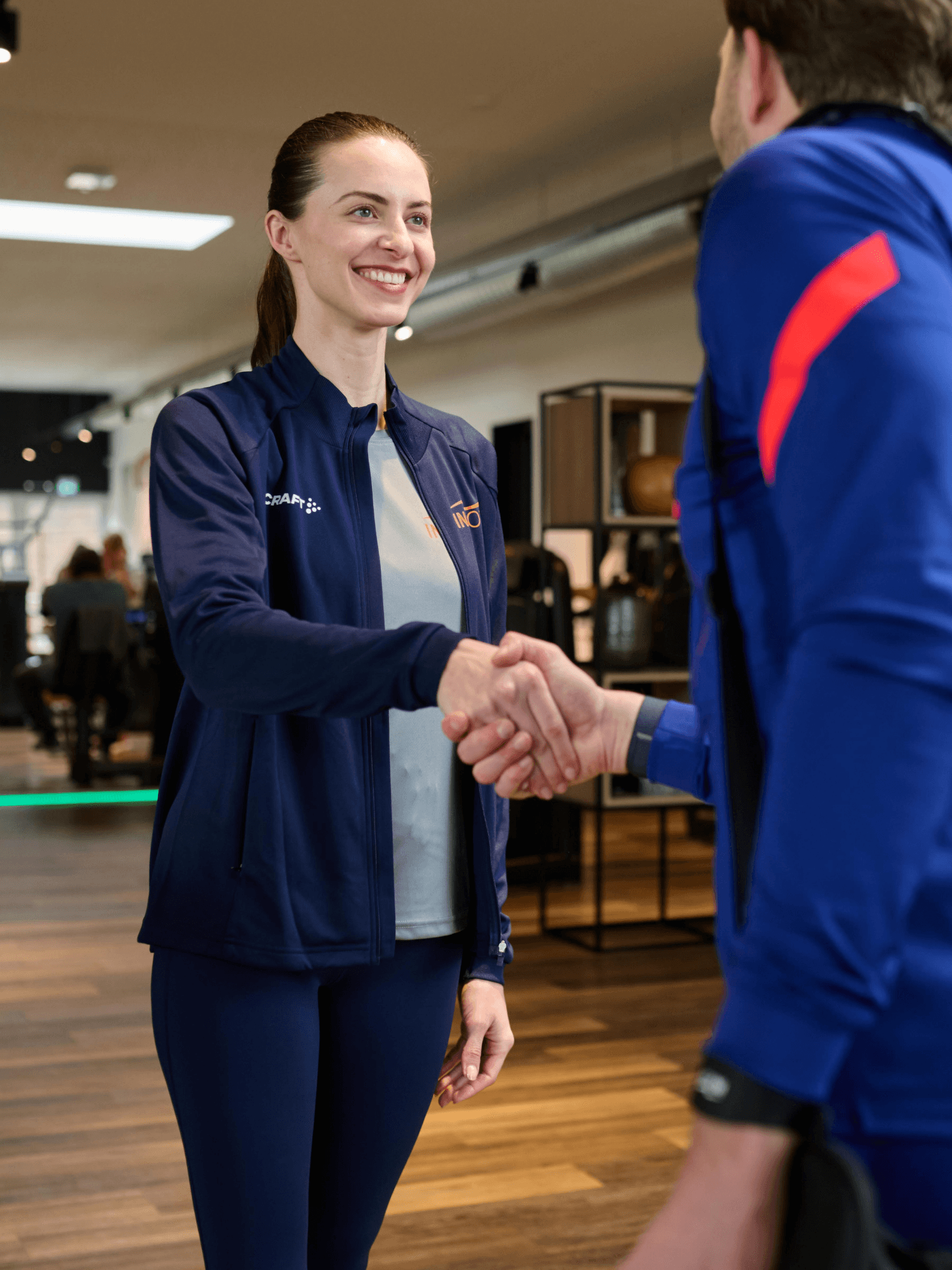 Eine INJOY Trainerin empfängt ein Mitglied im INJOY Fitnessstudio.
