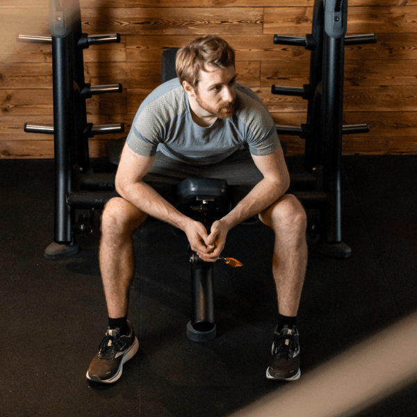 INJOY Mitglied sitzt auf Hantelbank und macht gerade eine Pause beim Training.